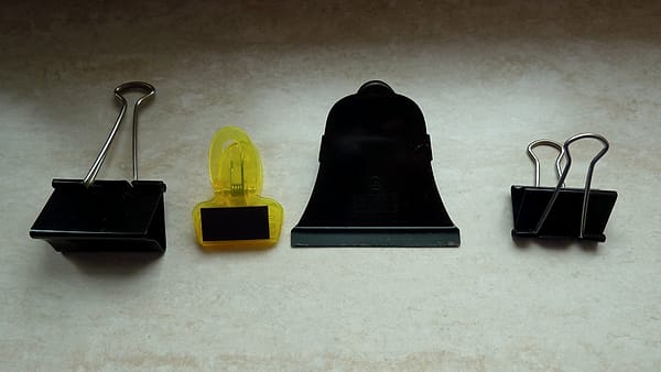 Binder clips in several sizes arranged together on a plain background