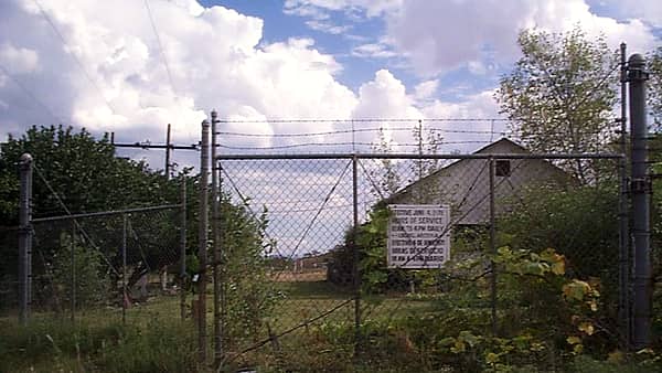 A closed border crossing station standing empty beside an unused road