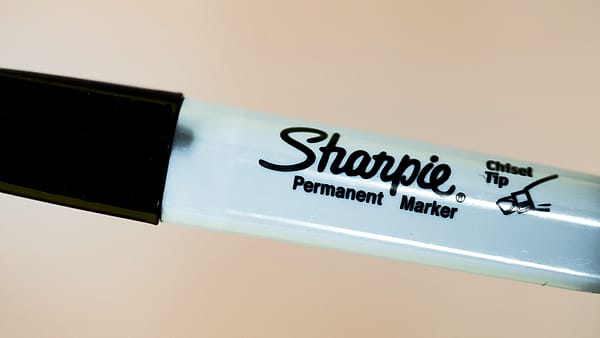 A black permanent marker with a chisel tip lying uncapped on a work surface