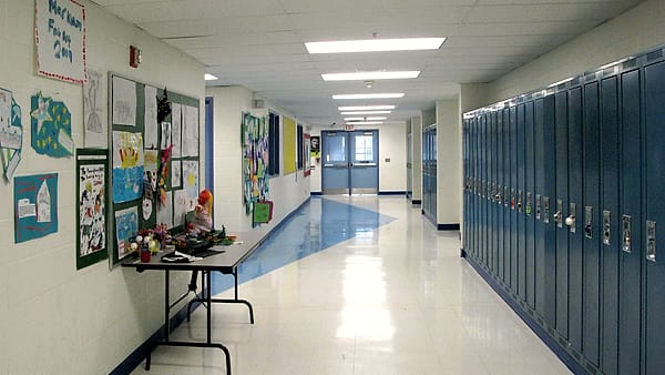 An empty school hallway lined with lockers and classroom doors
