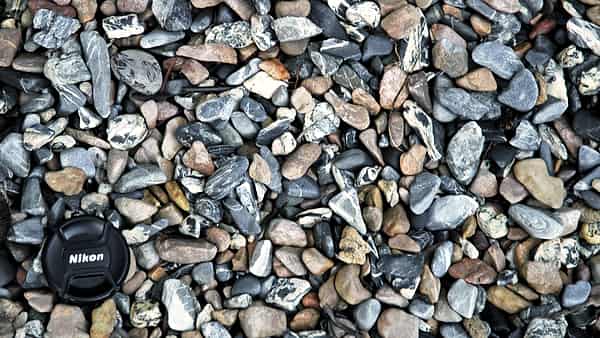 Small smooth pebbles lying together along a lake shoreline in daylight