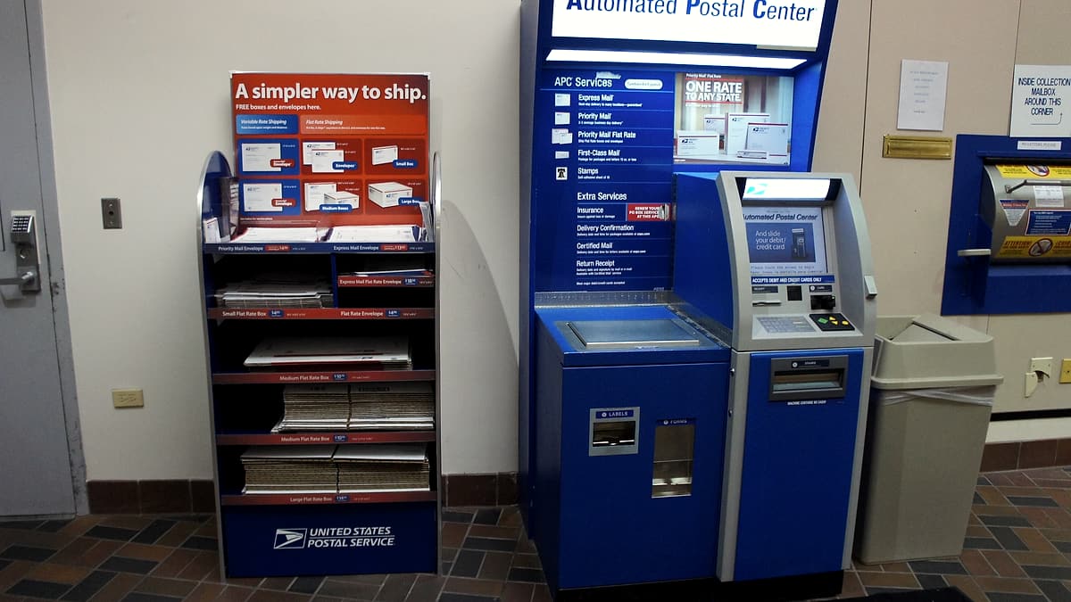 A self-service postal machine and mailing supplies in a post office lobby