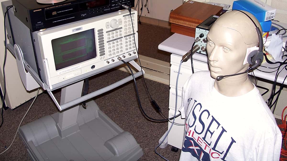 A call center headset resting on a desk beside audio testing equipment