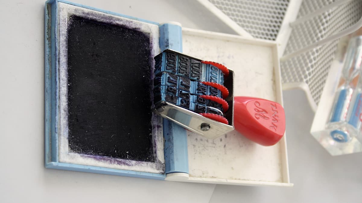 An office date stamp resting on an open ink pad on a wooden surface