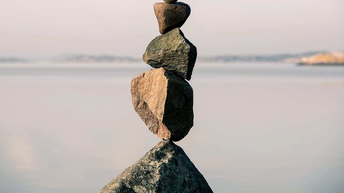 Four smooth stones balanced in a stack on a flat surface outdoors