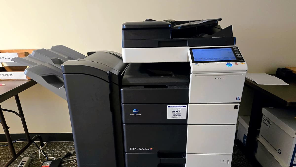 An office photocopier standing against a wall with its paper trays closed