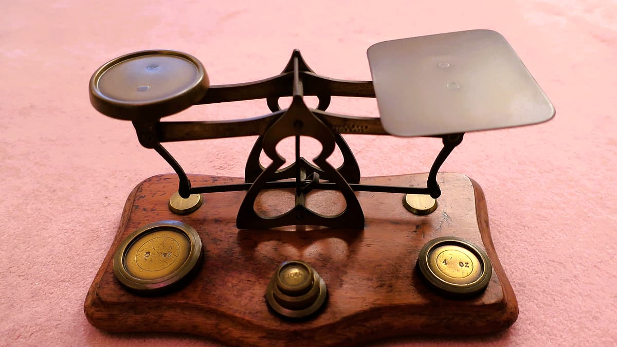 A set of brass balance scales with weights beside them on a table